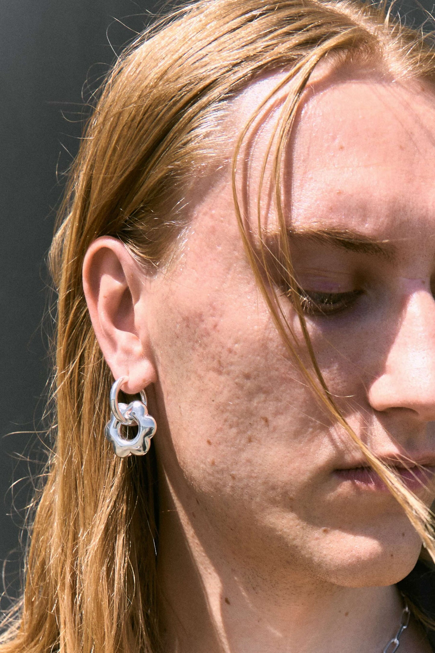 Man wearing large, puffy flower, silver hoop earring.