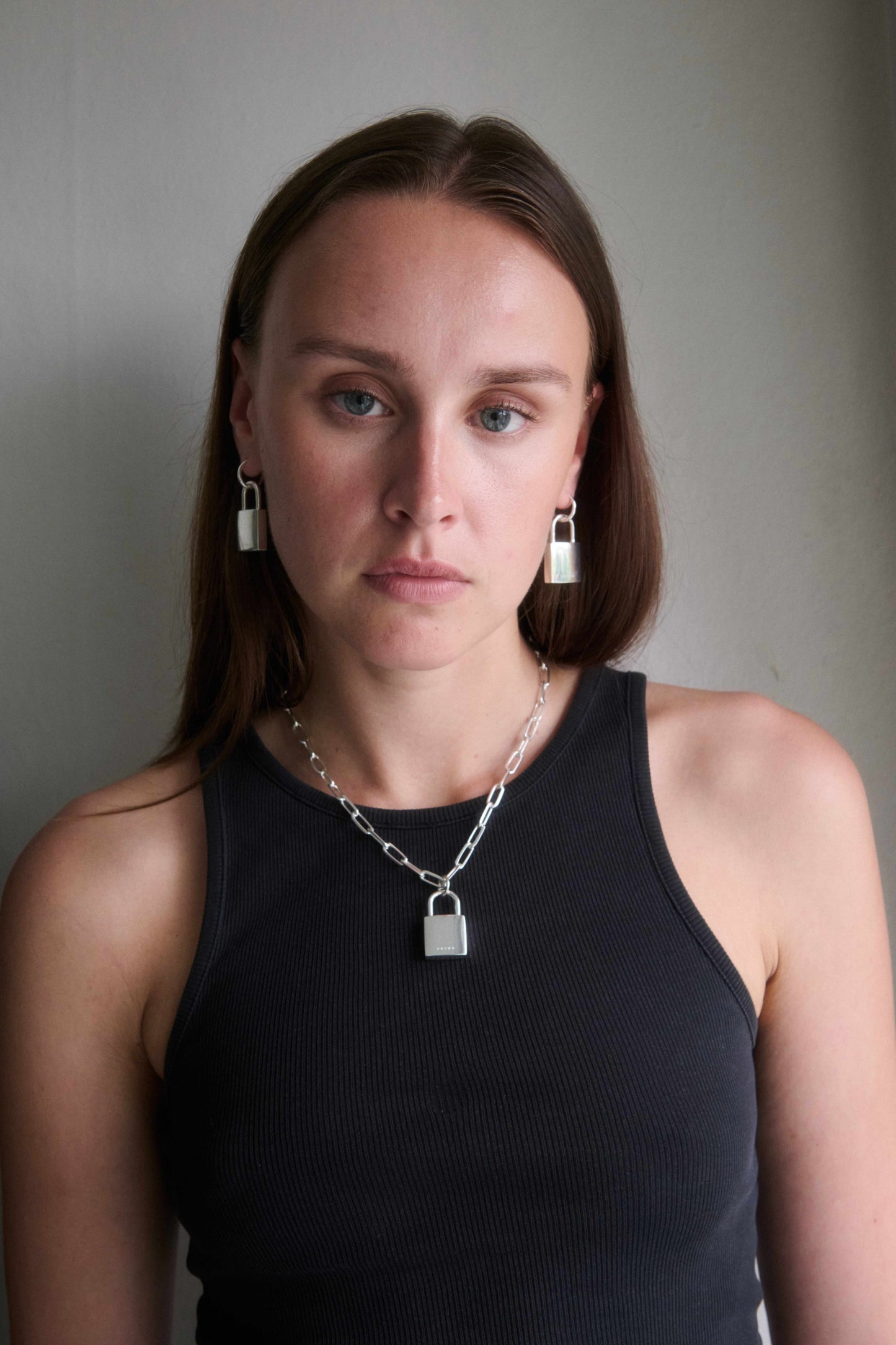 Silver padlock hoop earrings and padlock necklace worn by a woman
