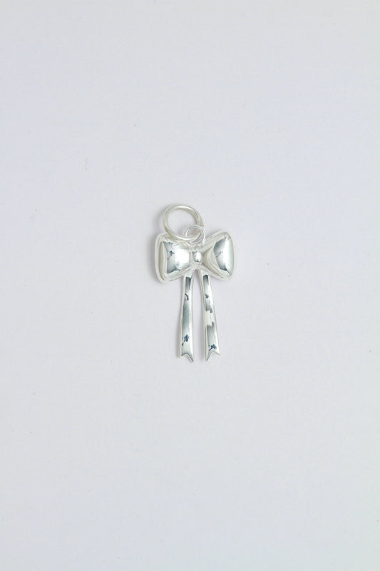Silver bow-shaped charm pendant that can be attached on a necklace or a hoop earring