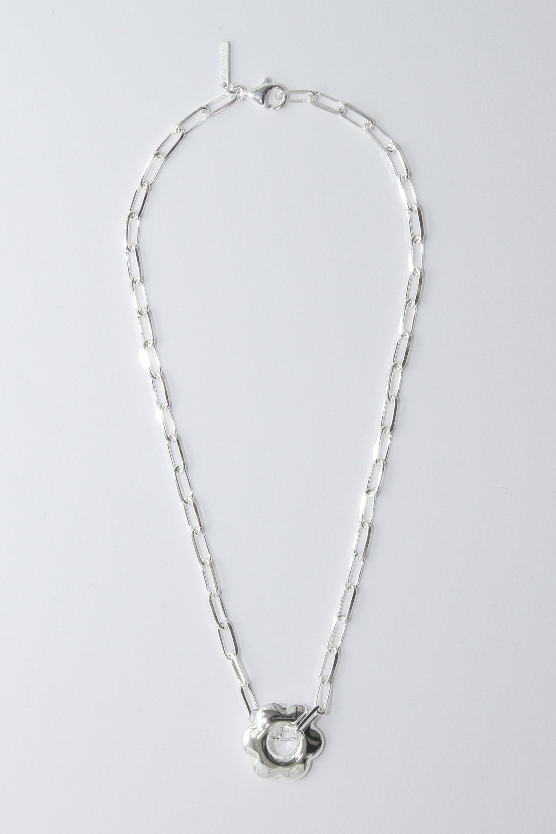 Silver necklace with a puffy, flower pendant on a light gray background