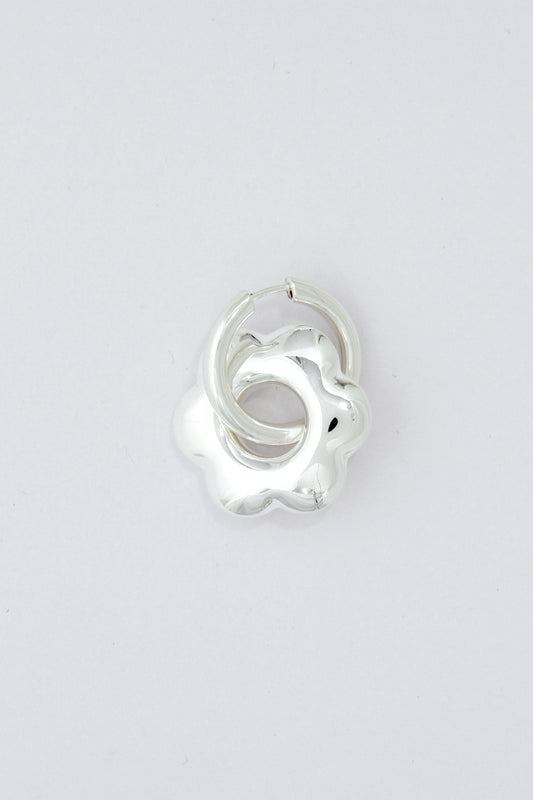 Large, puffy flower, silver hoop earring on a light gray background
