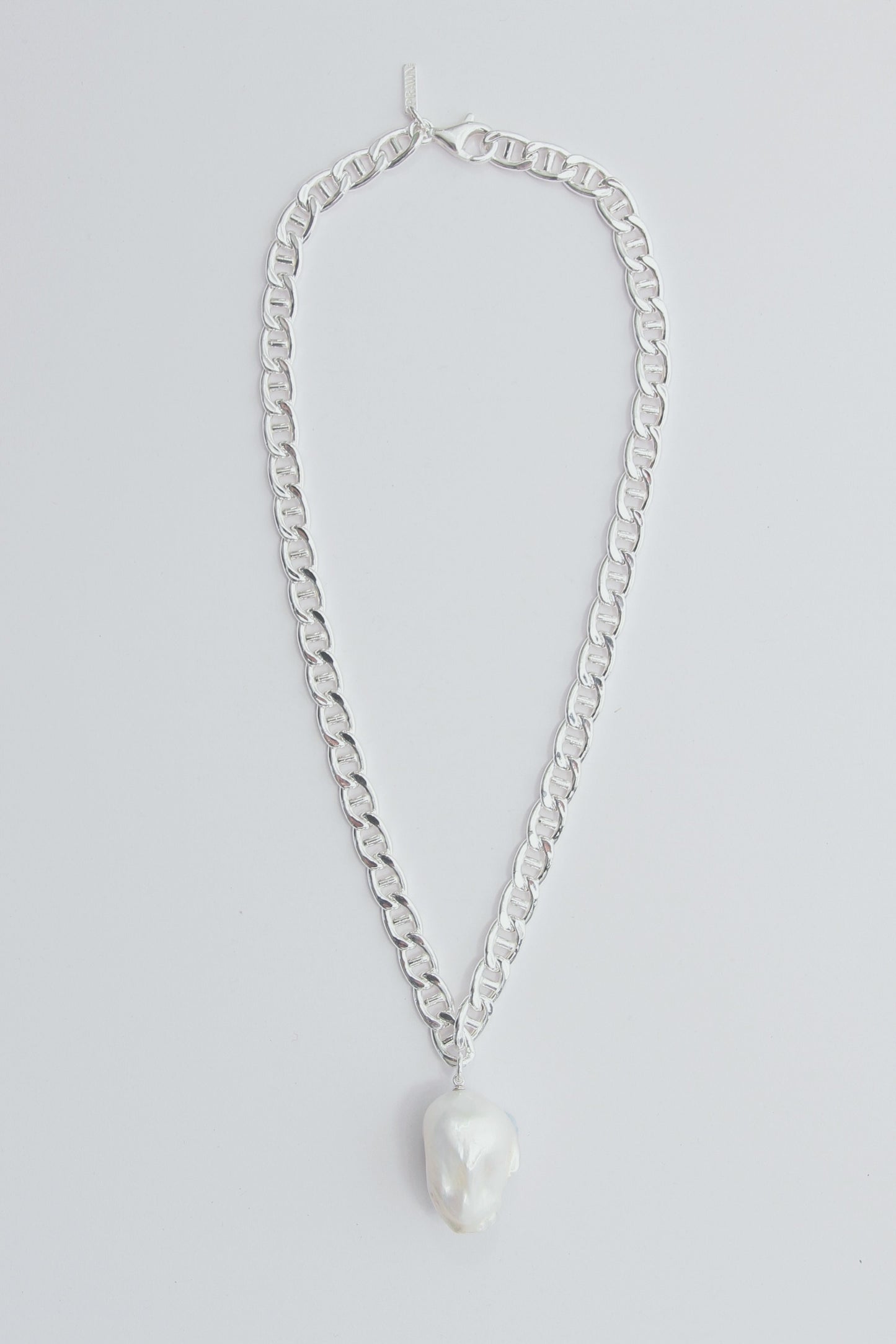 Chunky silver necklace with a large baroque pearl pendant.