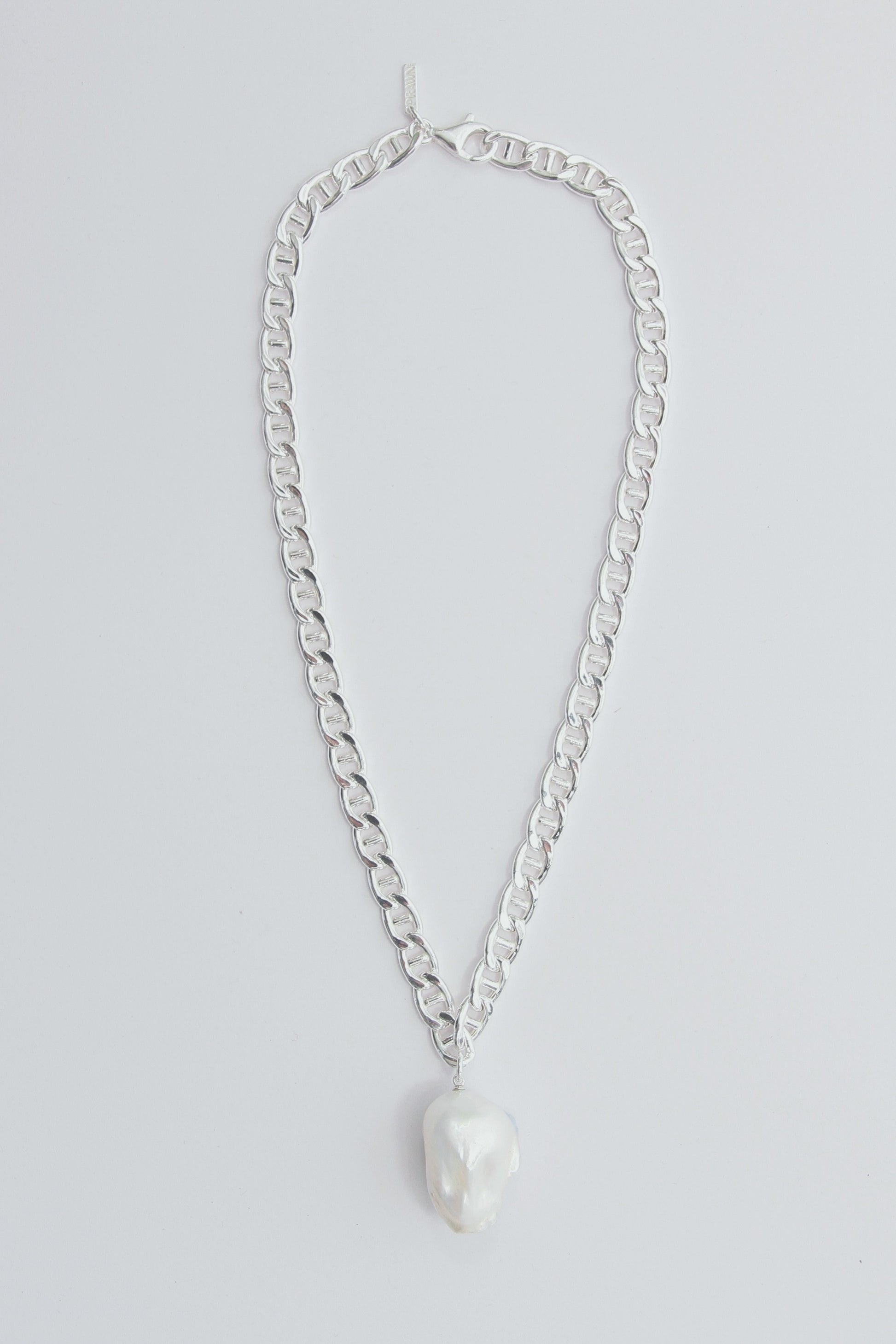 Chunky silver necklace with a large baroque pearl pendant.