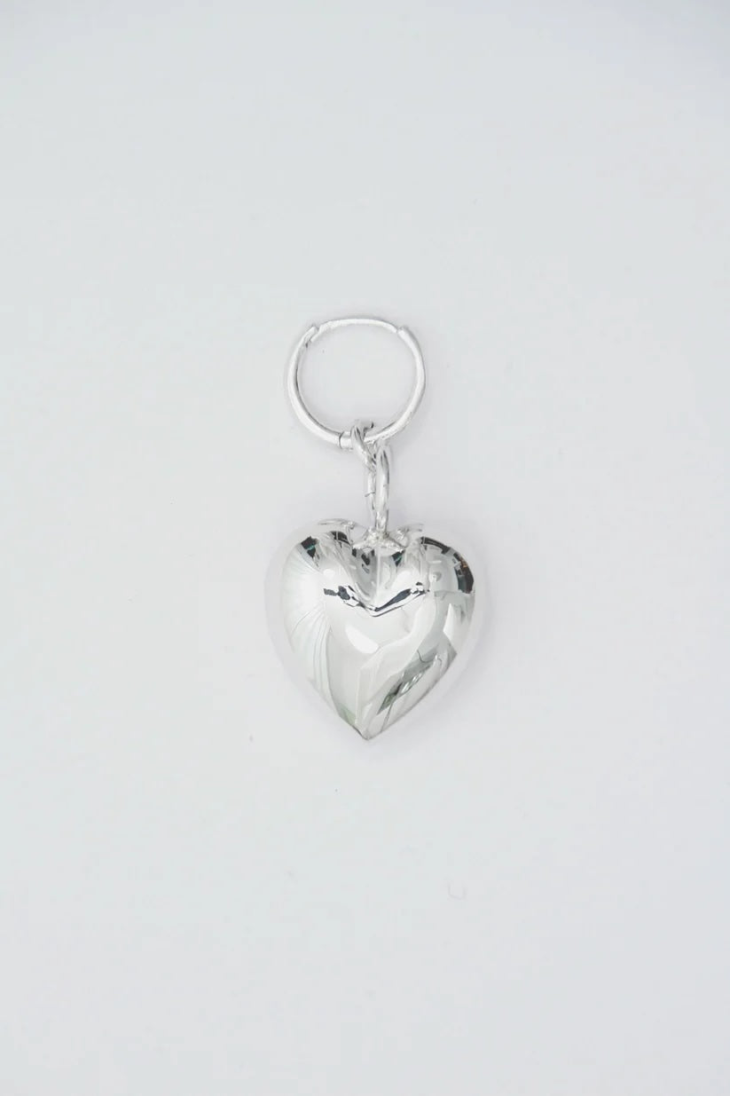 This image features a large, puffy heart hoop earring crafted from recycled 925 sterling silver. The earring is designed with a protective anti-tarnish coating to maintain its luster over time.